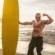 Older muscular man with surfboard