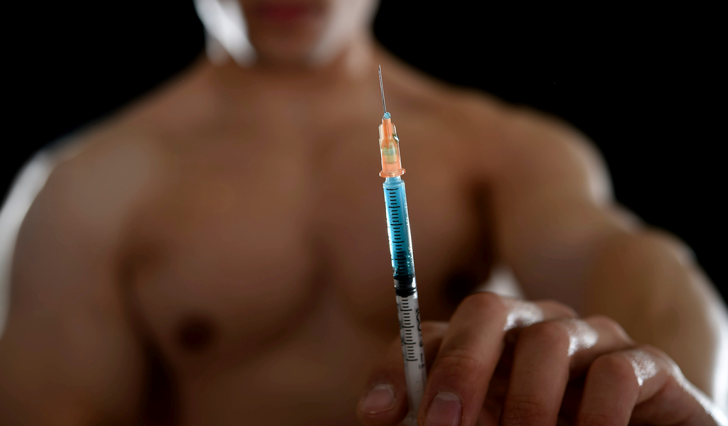 Male bodybuilder holding a syringe containing the steroid finabolan.