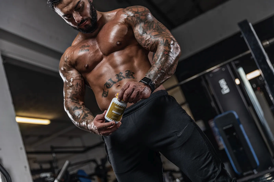 Picture of a male bodybuilder posing with a bottle of CrazyBulk Anadrole