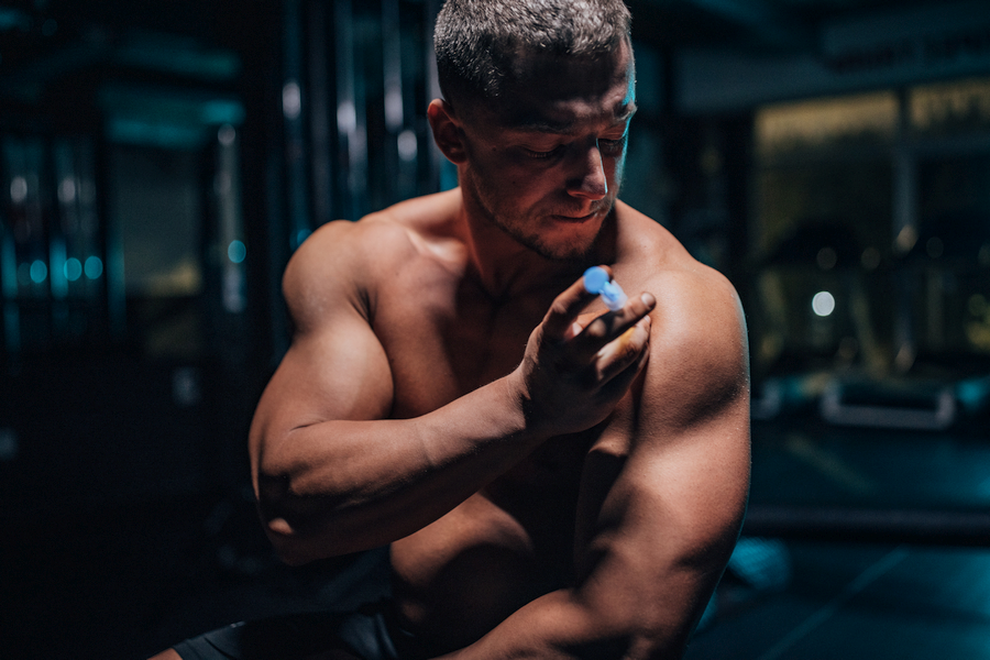 Image of a muscular man in a gym injecting anabolic steroids