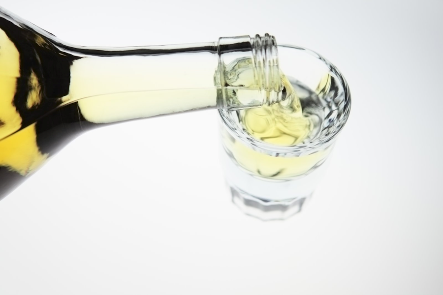 A bottle of liquor being poured into a glass