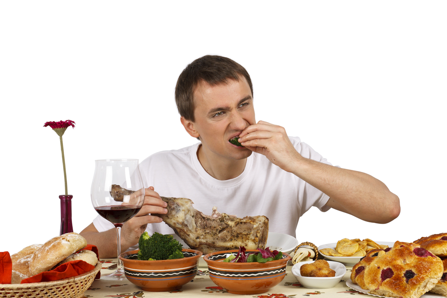 Young man sitting at a table covered in testosterone-killing foods