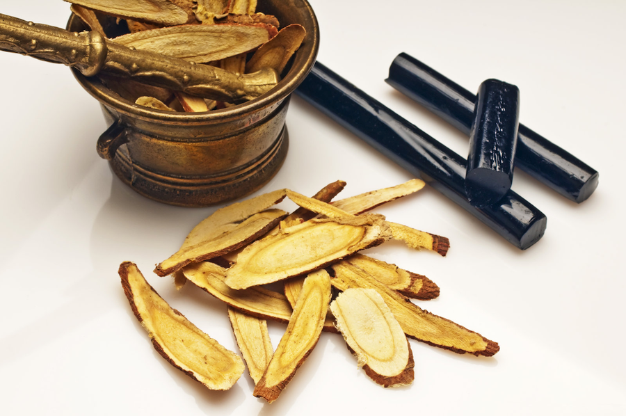 Fresh licorice root and candy on a white table